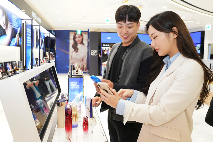  롯데면세점 스마트 스토어에서 휴대폰으로 제품 정보를 확인하고 있는 소비자들.