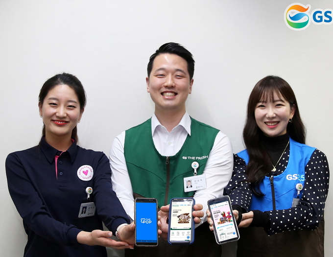 GS리테일 직원들이 휴대폰으로 THE POP 애플리케이션을 실행하고 있다.
