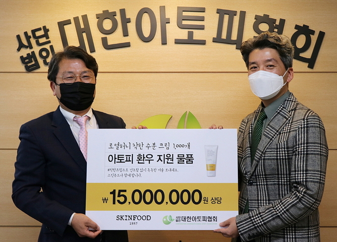 (왼쪽부터) 김현지 스킨푸드 마케팅본부장이 최성래 대한아토피협회 사무총장에게 수분 크림 1천개를 전달했다.