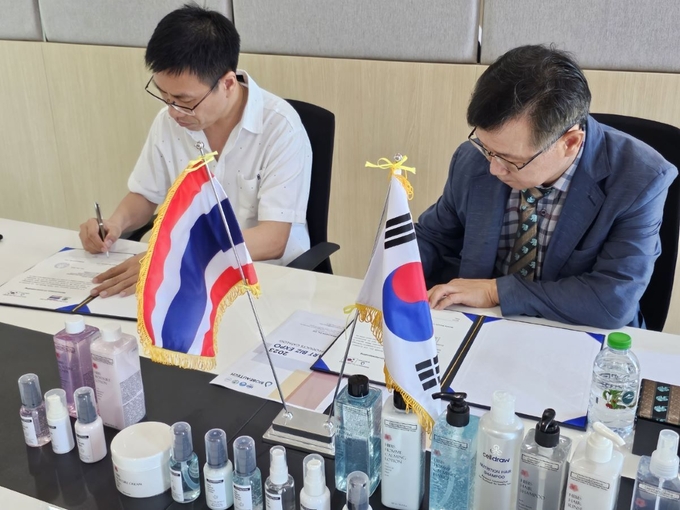  김인영 (주)바이오뷰텍 대표<사진 오른쪽>가 태국 네이처 베네피트사와의 협력 생산 MOU 체결식에서 서명하고 있다. 