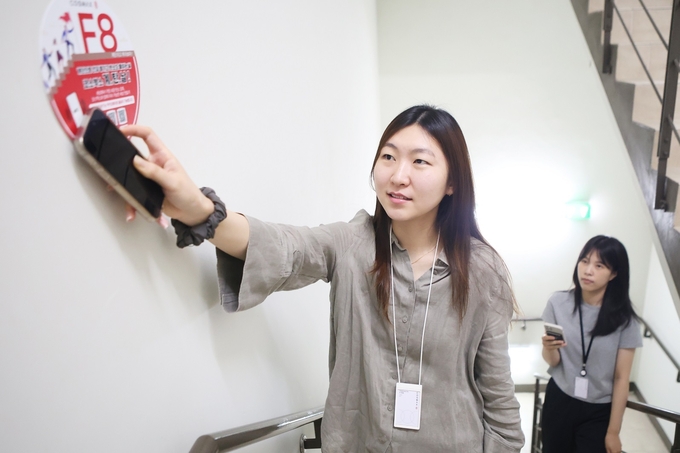 출근 중인 코스맥스 직원이 임직원 참여형 탄소 감축 프로그램 '계탄날'에 참여하기 위해 계단 표지에 스마트폰을 접촉하고 있다.