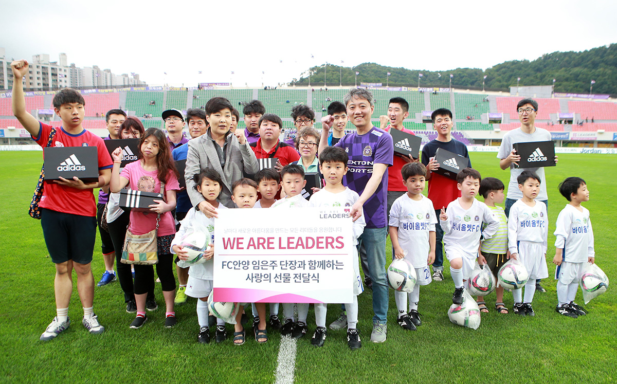 FC안양 임은주 단장(왼쪽)과 리더스코스메틱 김기현 마케팅 본부장(오른쪽)이 위 아 리더스 캠페인 후원 수혜자들과 기념사진을 촬영하고 있다.
