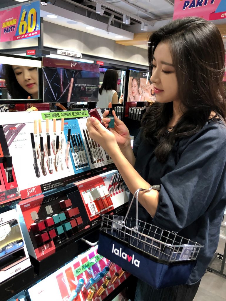 고객이 랄라블라 매장에서 삐아의 브라운 색 립 제품을 살펴보고 있다.